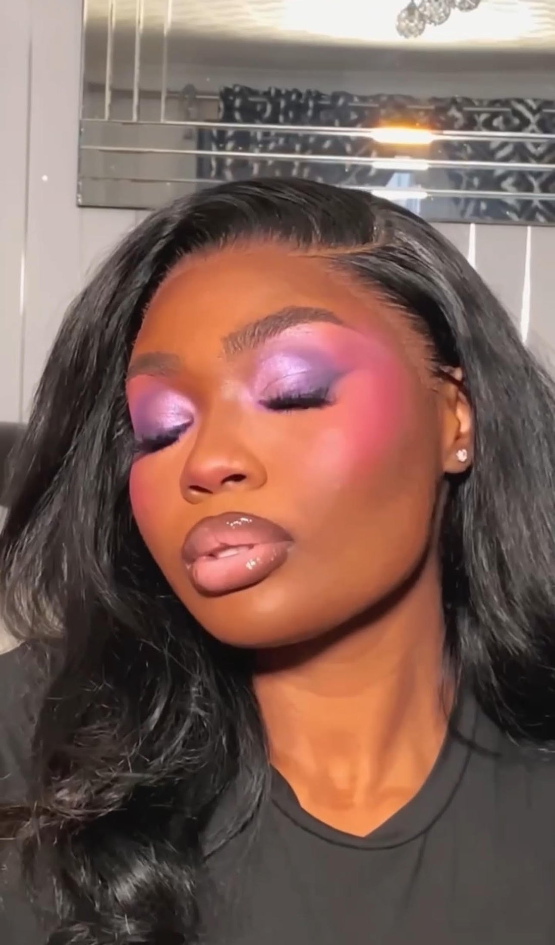 An individual wearing false lashes from Lahira Lashes with pink and purple eyeshadow, glowing makeup, and glossy nude lips.